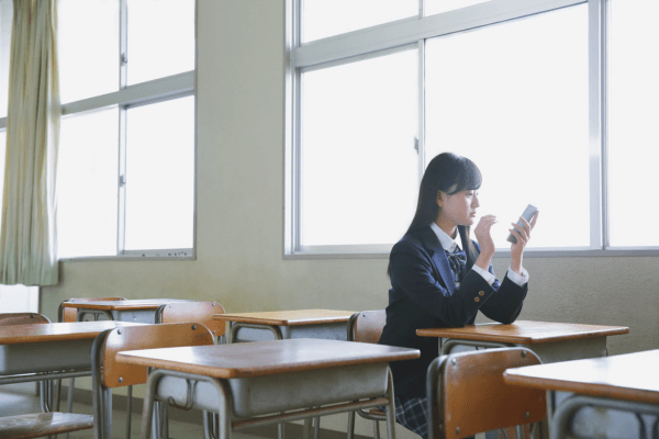 窓際でスマホを見る女子高生